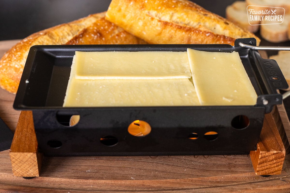 Unmelted cheese over candles in raclette dish.