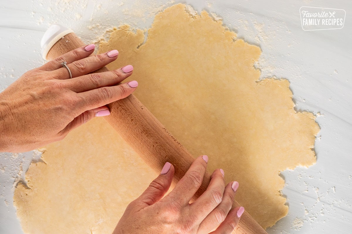 Rolling out pastry dough on floured surface.