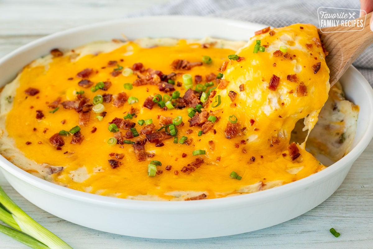 Wooden spoon scooping a serving of Loaded Mashed Potatoes.