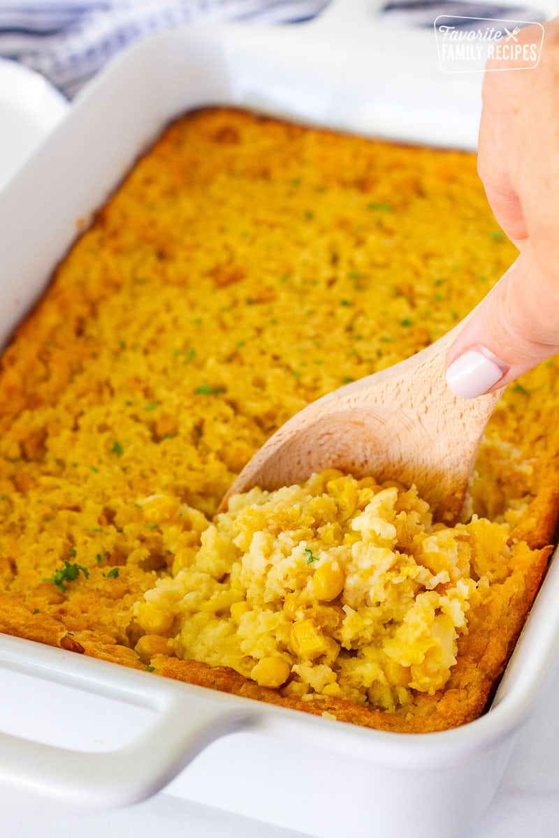 Spoon scooping into a baked Southern Corn Casserole with whole corn kernels.