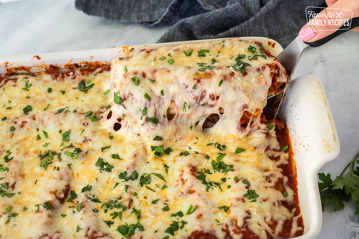 Lifting up Chicken and Spinach Manicotti shells from baking dish.