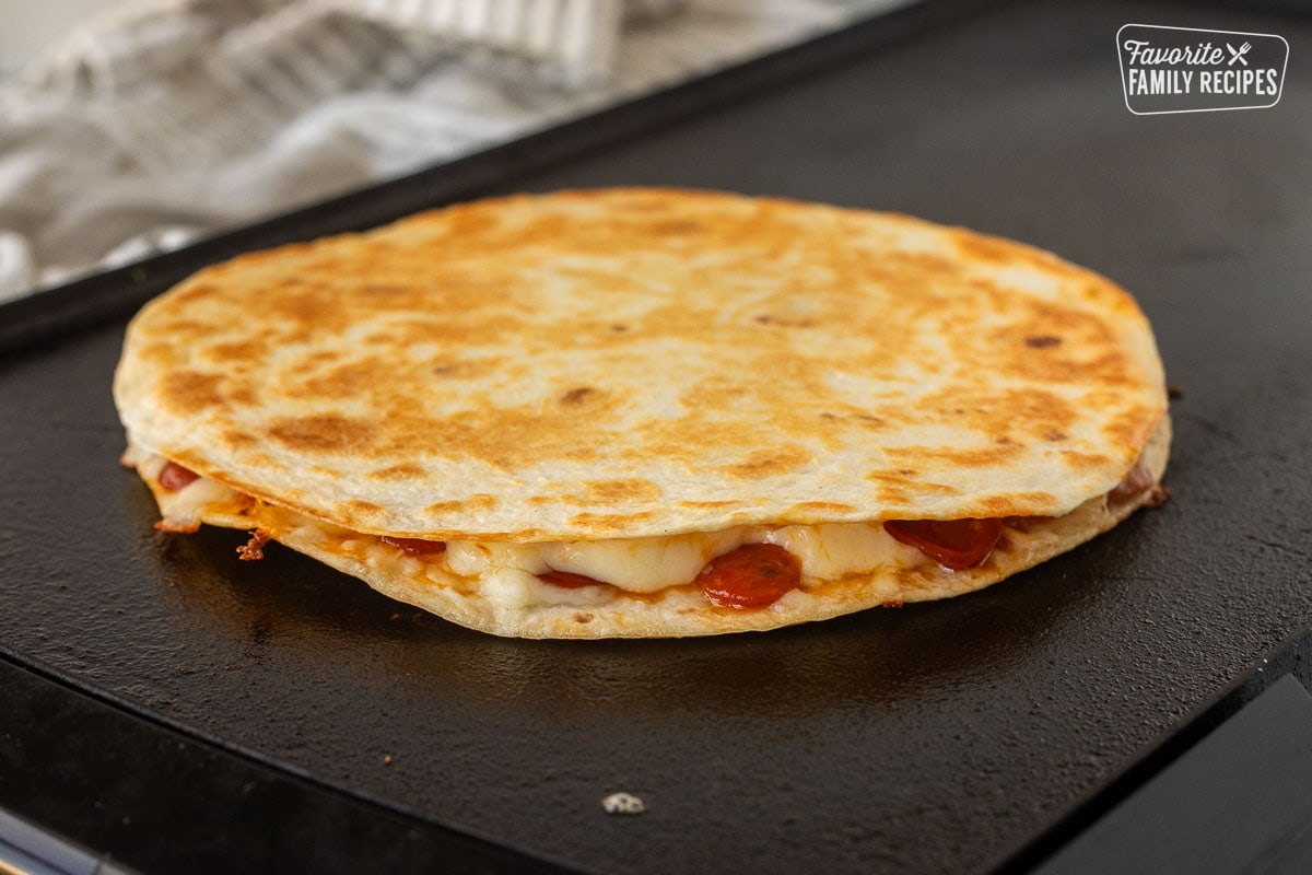 Side view of Pizza Quesadilla with melted cheese on a skillet.