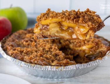 Hand holding a slice of Gluten Free Apple Pie over the pie.