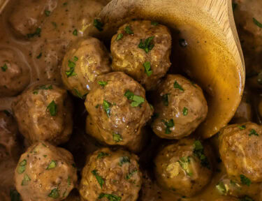 Crock Pot of Swedish Meatballs with a wooden spoon.