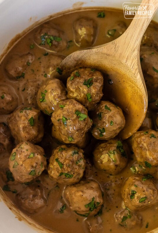 Crock Pot of Swedish Meatballs with a wooden spoon.