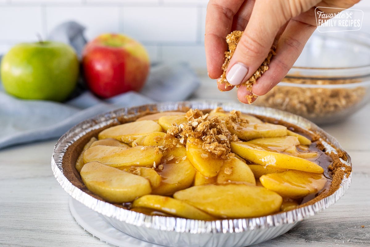 Hand sprinkling crumble topping on Gluten Free Apple Pie.