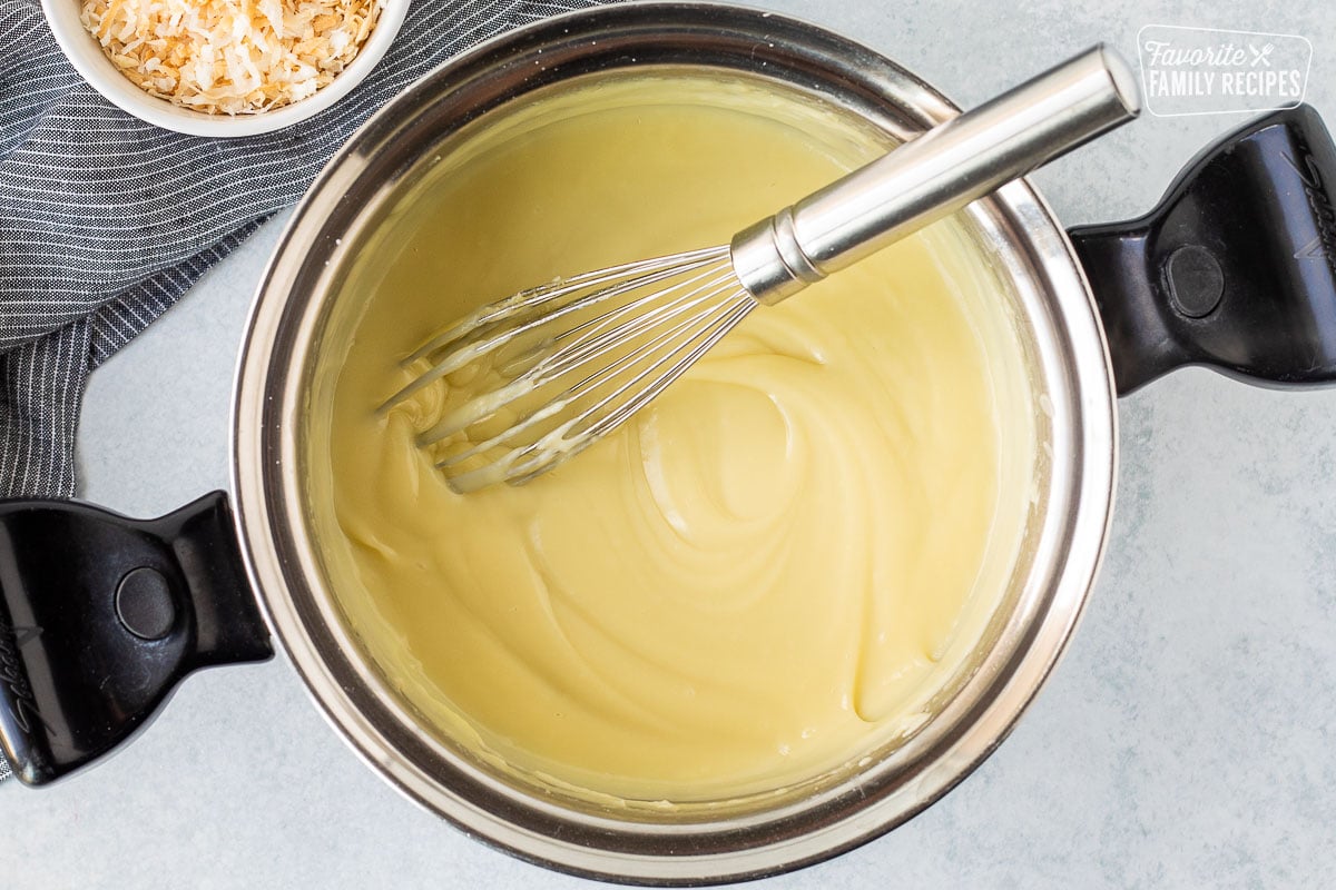 Sauce pan with thickened pudding mixture and a whisk.