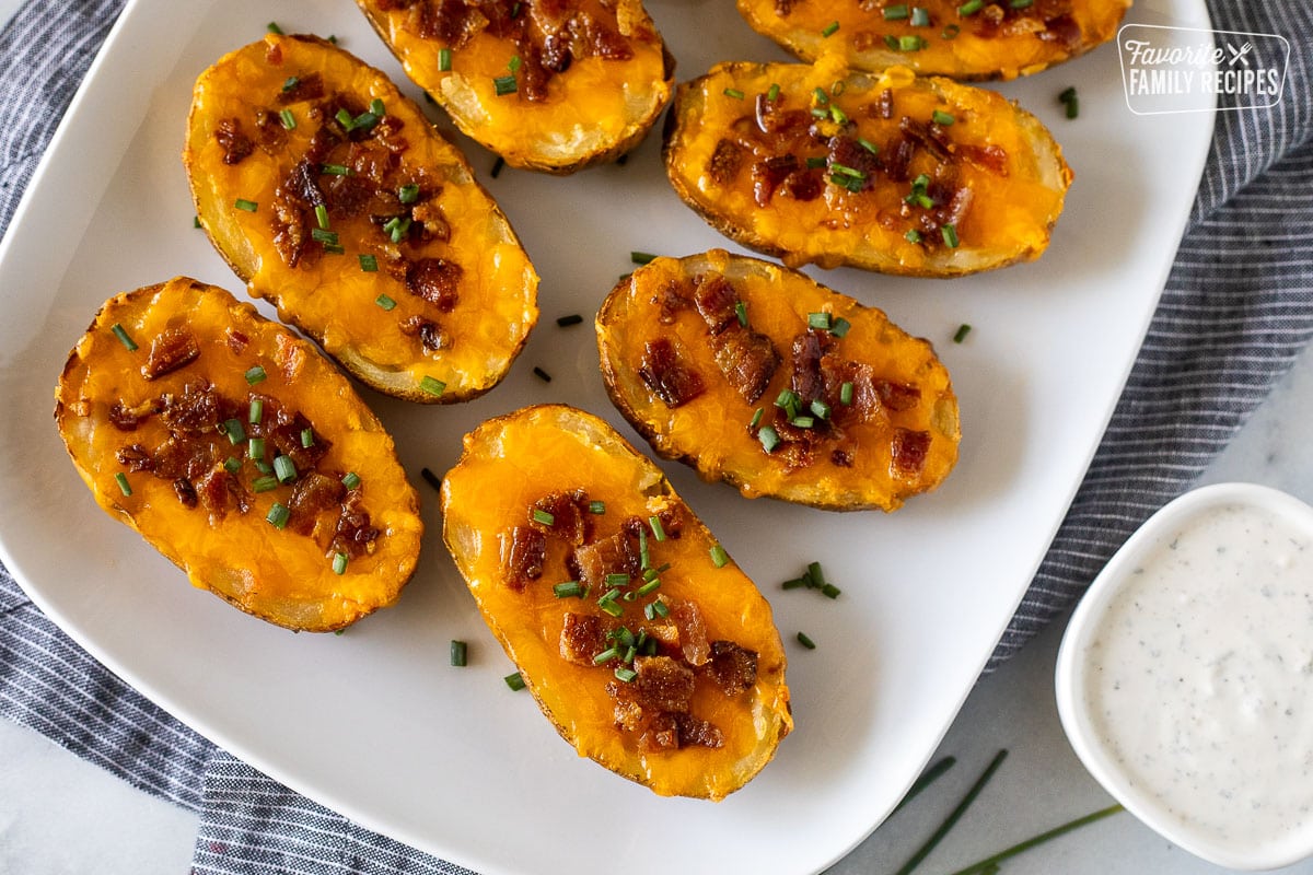 Loaded potato skins on a platter with bacon, cheese and chives