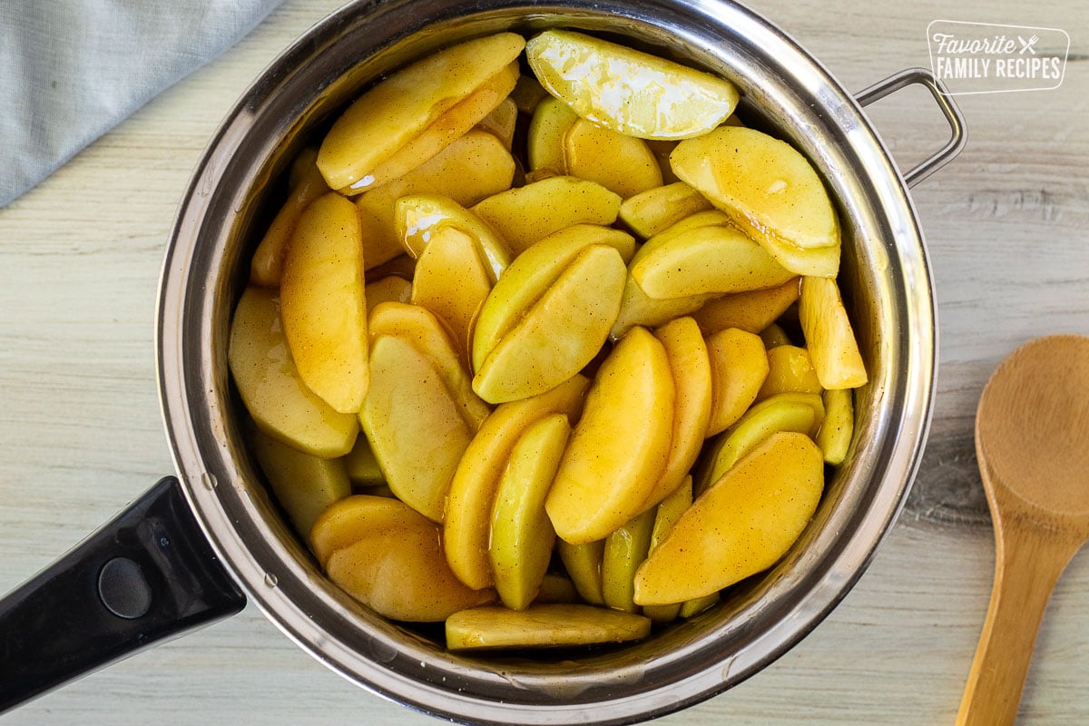 Pan of sliced apples with glaze. Wooden spoon on the side.