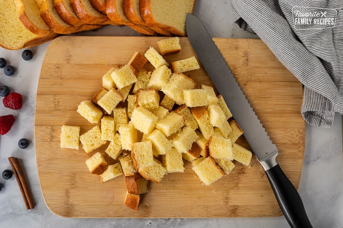 Cutting board with a bread, knife and cubed brioche bread.