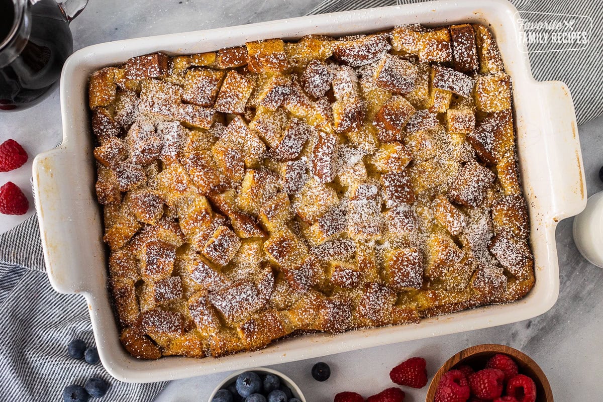 Baking dish of brioche French toast casserole dusted with powdered sugar.