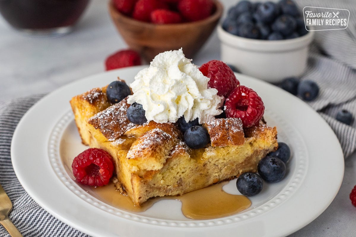 Plate with brioche French toast casserole, fresh blueberries, and raspberries and syrup.