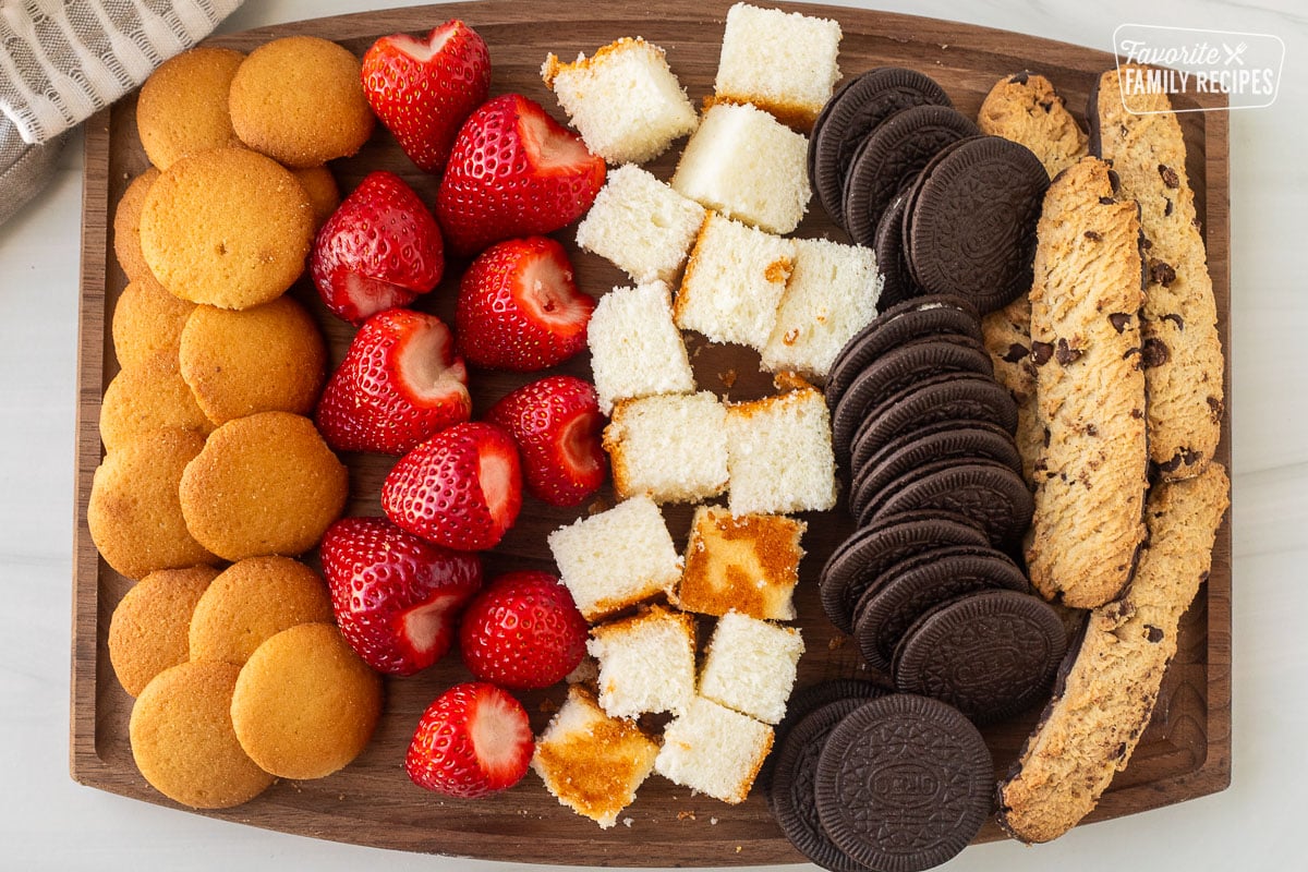 Cutting board with strawberries, angel food cake, Oreos, cookies, and vanilla wafers.