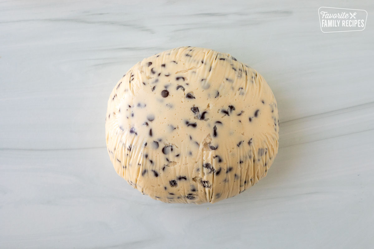 Ball of Chocolate Chip Cheese Ball wrapped in plastic wrap.