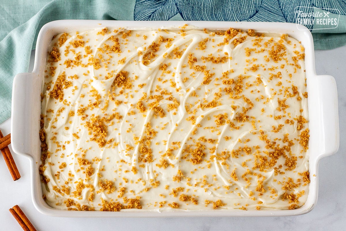 Cinnamon crumble on top of frosted Cinnamon roll cake in a baking dish.