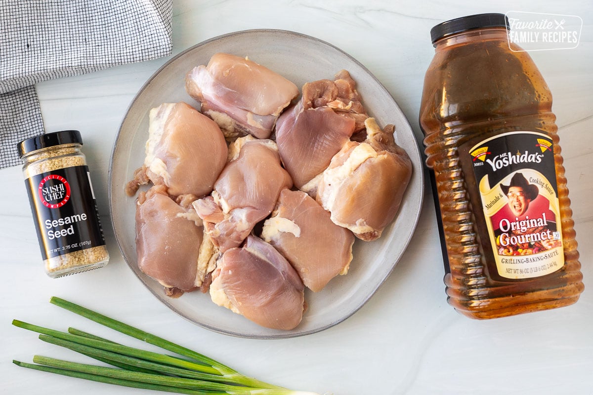 Ingredients to make crockpot, Hawaiian chicken, including Mr. Yoshida's sauce, chicken thighs, sesame seeds, and green onion for garnish.