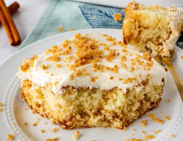 Slice of cinnamon roll cake on a plate with a fork.