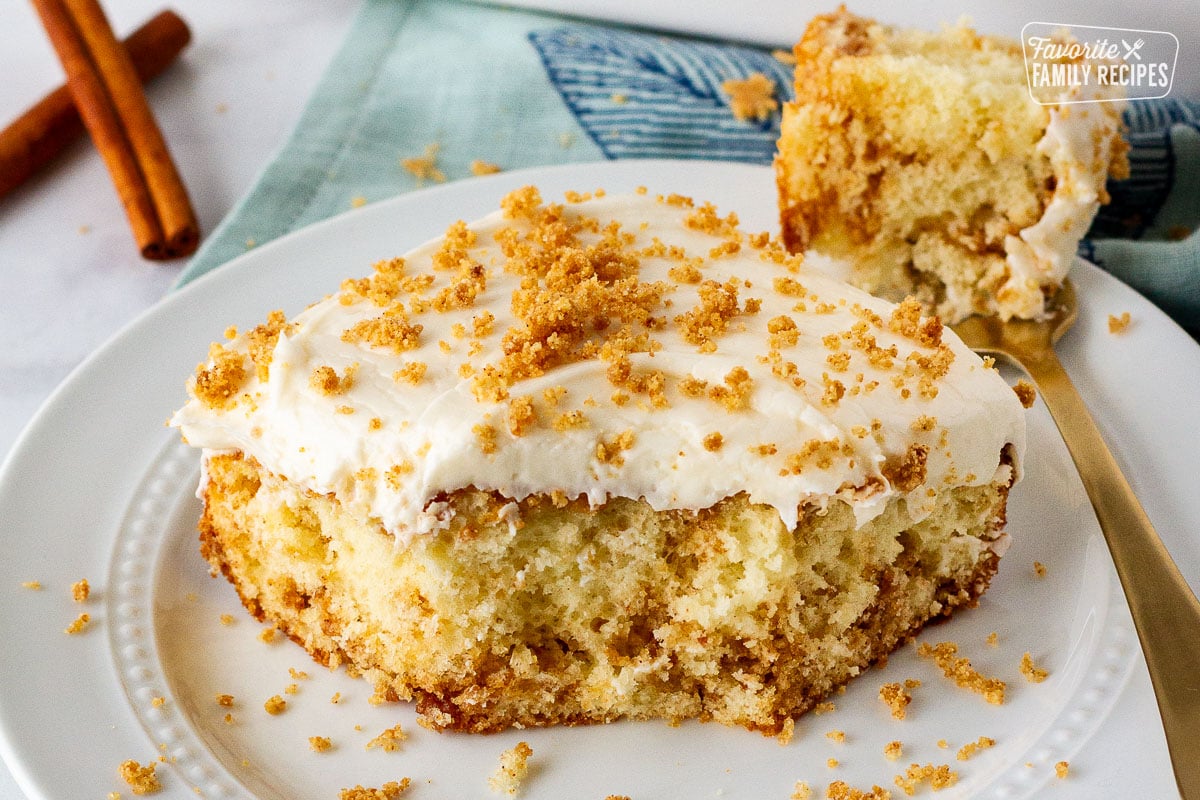 Slice of cinnamon roll cake on a plate with a fork.