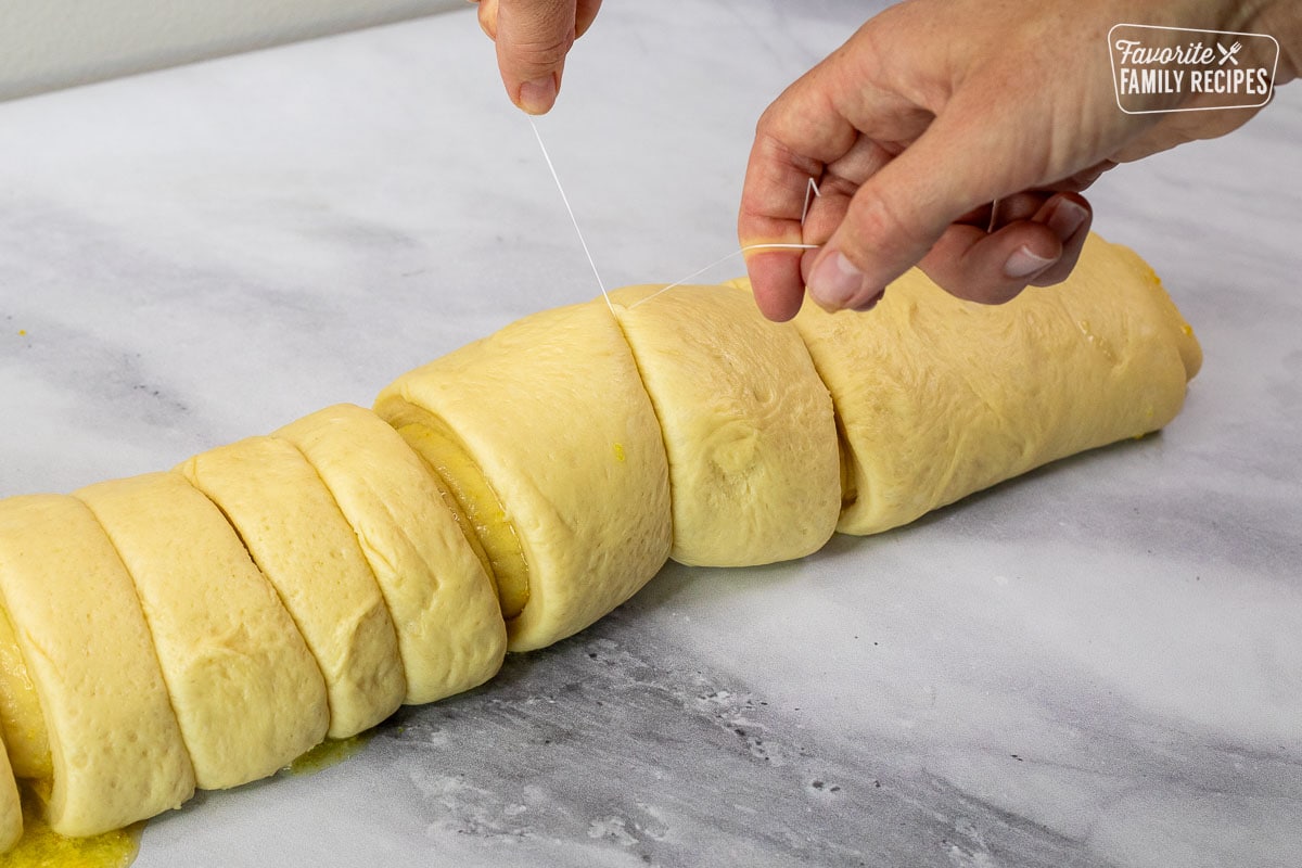 Cutting homemade orange rolls with floss.