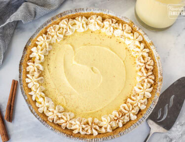 Whole egg nog pie decorated with whipping cream and cinnamon.