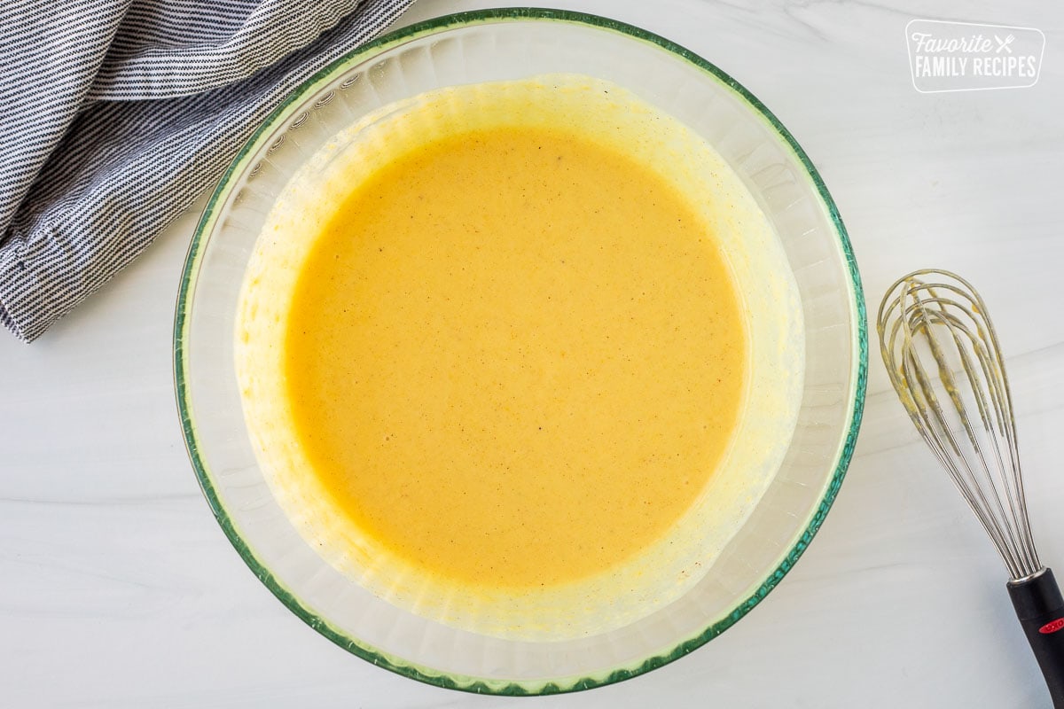 Mixing bowl with egg nog pie filling and a whisk on the side.