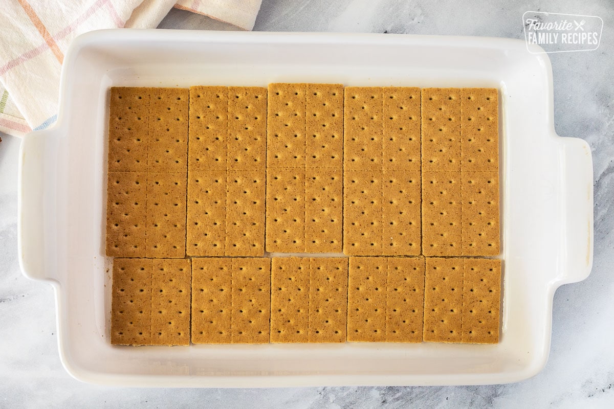 Baking dish with graham crackers on the bottom layer to make Pumpkin Eclair Cake.