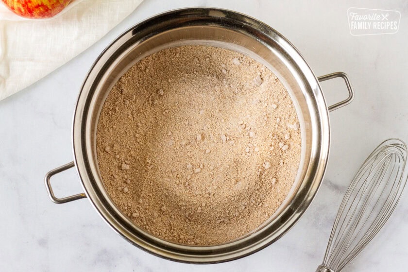 Saucepan of sugar mixture for Homemade Apple Pie filling next to a whisk.