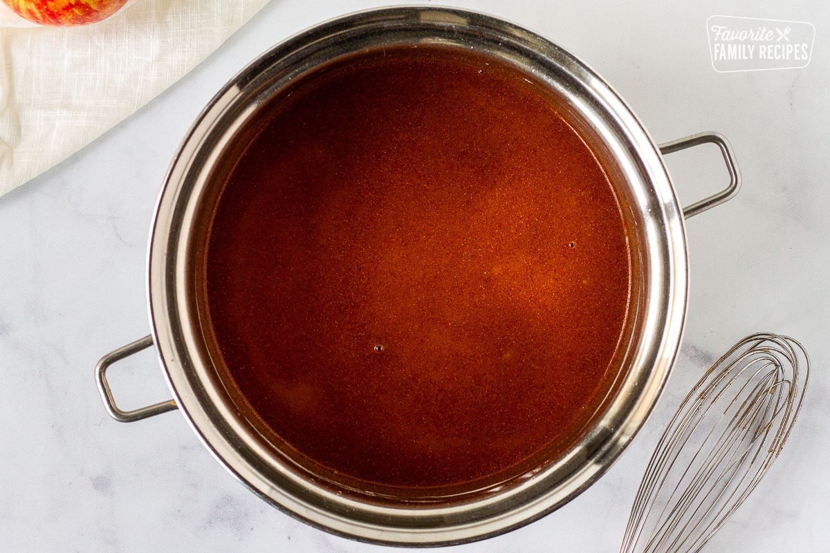 Saucepan with mixture for Homemade Apple Pie filling next to a whisk.