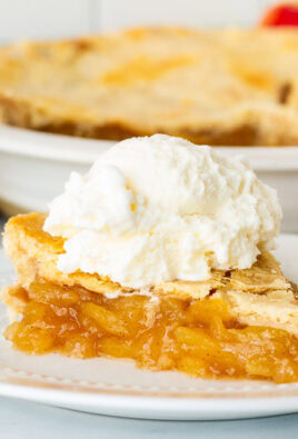 Side view of Homemade Apple Pie topped with a large scoop of vanilla ice cream. Whole pie in the background.