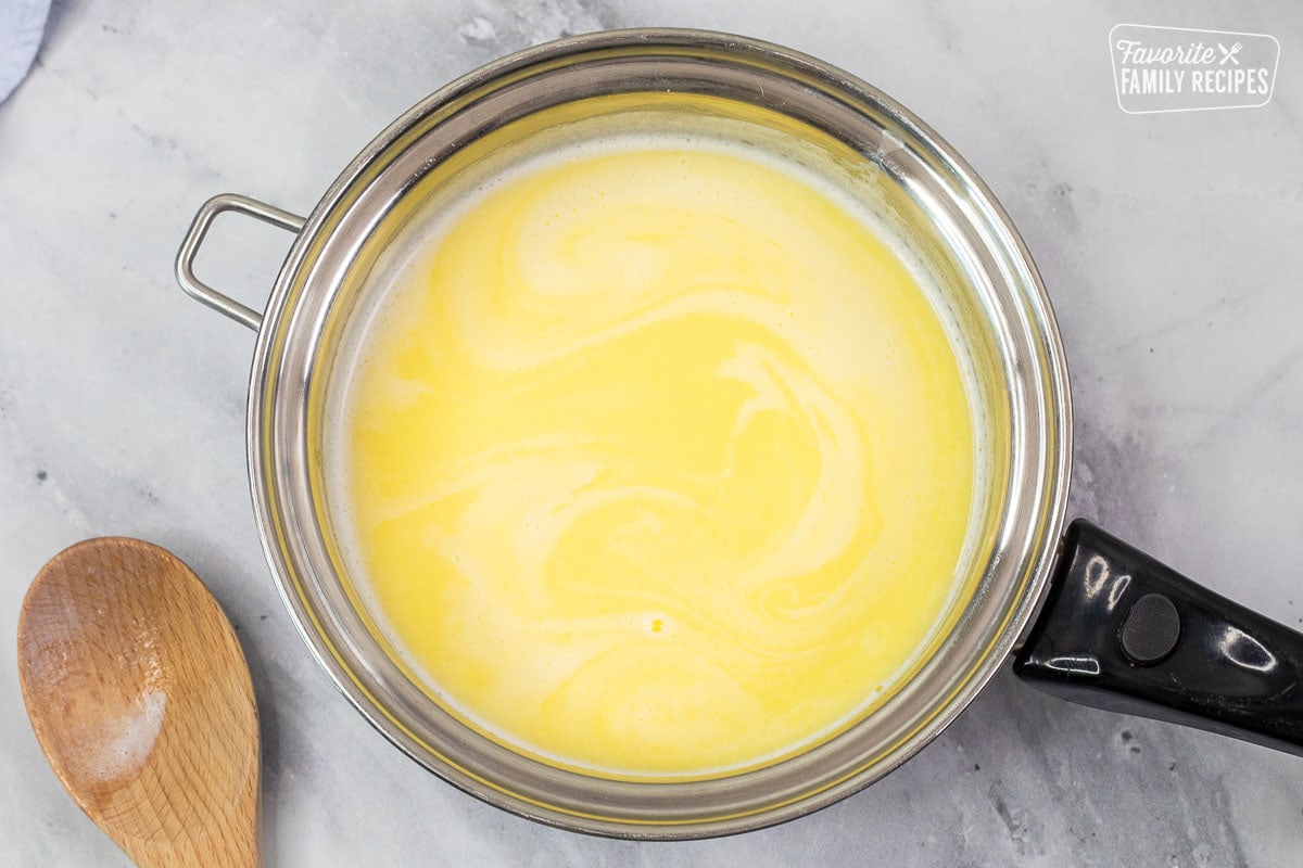 Sauce pan with melted milk and butter. Wooden spoon on the side.