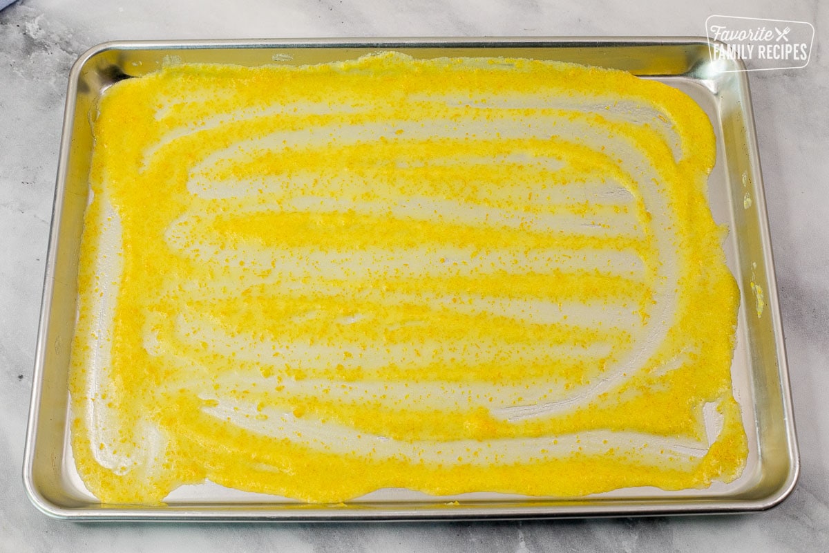 Baking sheet covered in orange glaze sauce.