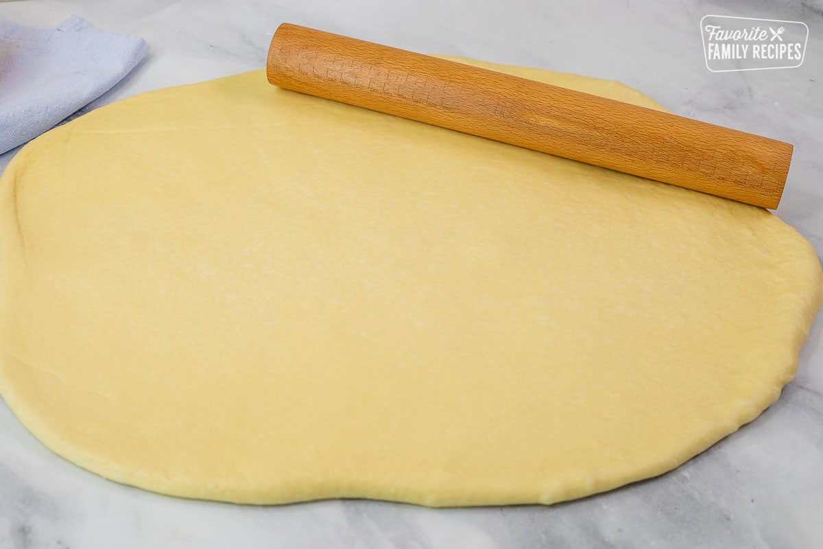 Rolled out bread dough with a wooden roller.