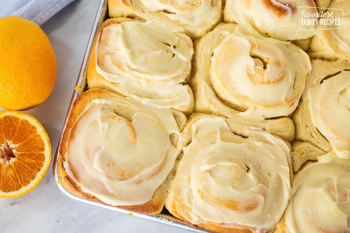 Frosted homemade orange rolls in a baking pan.