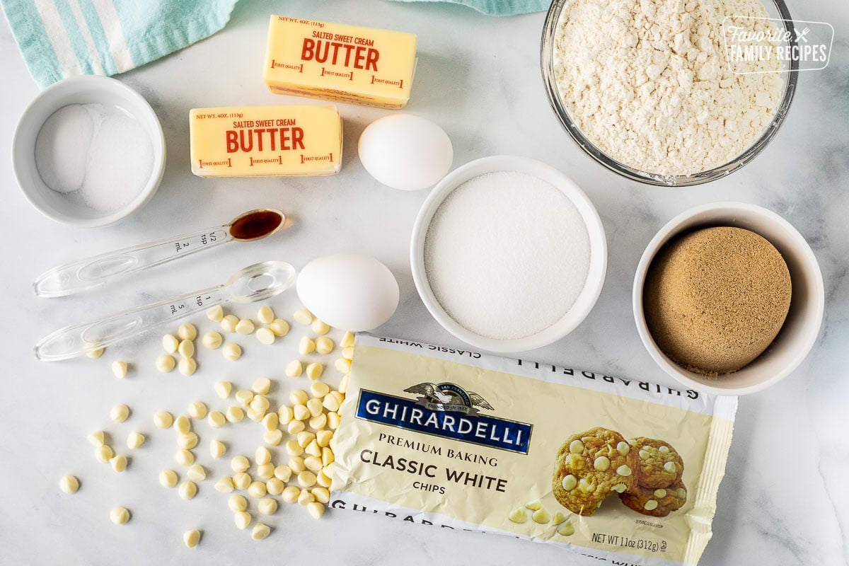 Ingredients to make White Chocolate Chip Cookies including butter, salt, baking soda, eggs, vanilla, almond extract, flour, sugar, brown sugar and Vanilla baking chips.