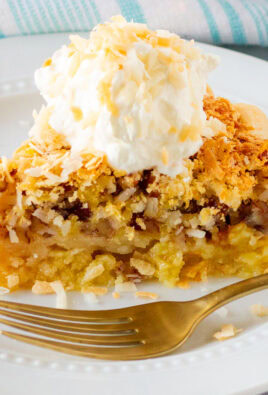 Slice of Island Pecan Pie on a plate topped with whipped cream and toasted coconut.