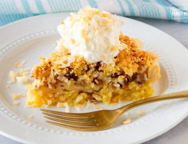 Slice of Island Pecan Pie on a plate topped with whipped cream and toasted coconut.