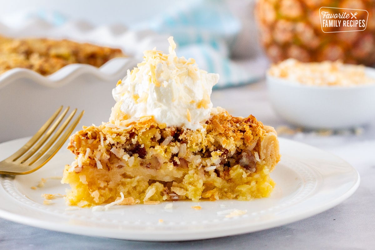 Slice of Island Pecan Pie on a plate topped with whipped cream and toasted coconut.