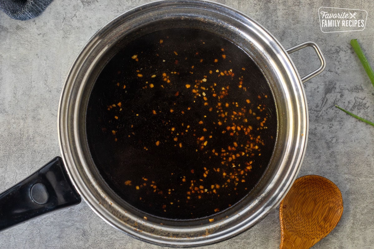 Saucepan with soy sauce, mixture for Mongolian beef. Wooden spoon on the side.