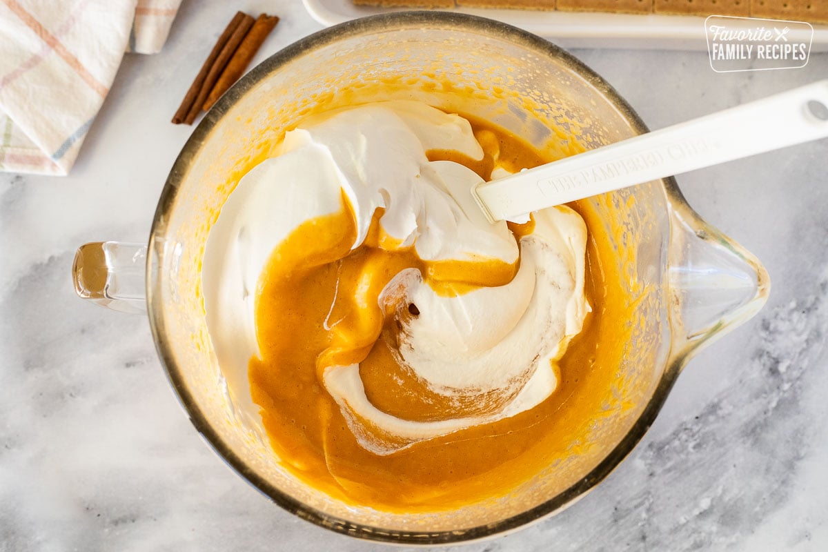 Mixing bowl with pumpkin pudding and Cool Whip for Pumpkin Eclair Cake.