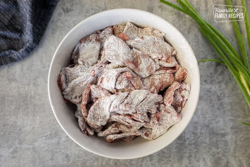 Bowl of sliced steak covered in cornstarch.