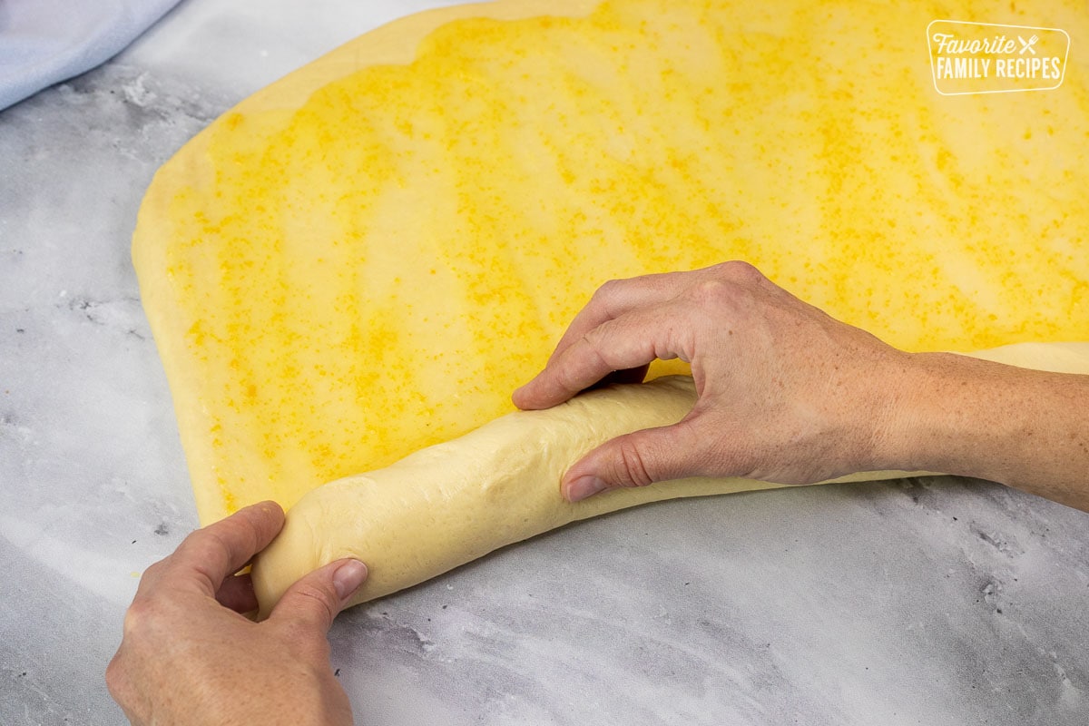 Rolling homemade orange rolls by hand.