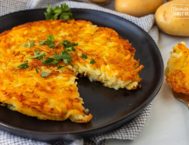 Rosti on a plate garnished with parsley and a cut out with a fork.