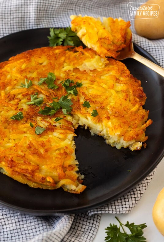 Rosti on a plate garnished with parsley and a cut out with a fork.