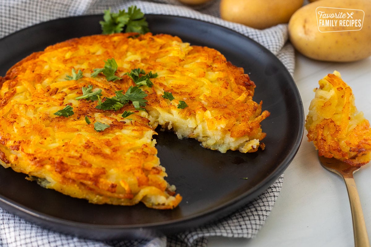 Rosti on a plate garnished with parsley and a cut out with a fork.