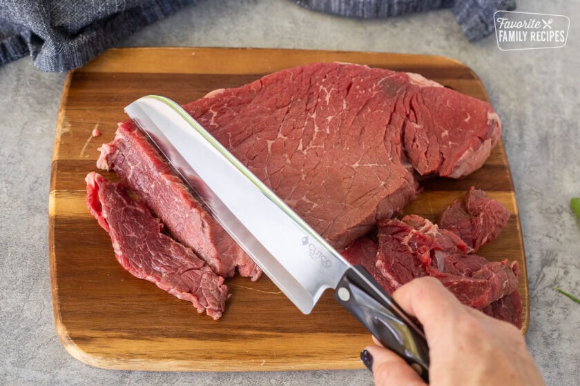 Cutting board with steak and a knife.