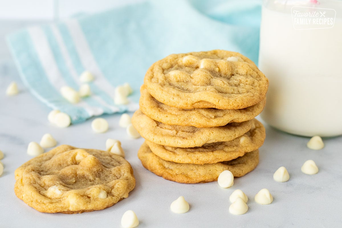 Stack of White Chocolate Chip Cookies with a tall glass of milk and white chocolate chips