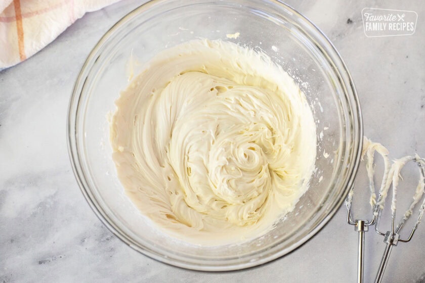 Frosting in mixing bowl with beaters for Pumpkin Eclair Cake.