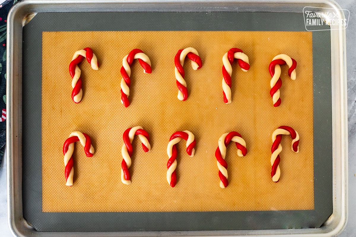 Unbaked candy cane cookies on a baking silicone mat.