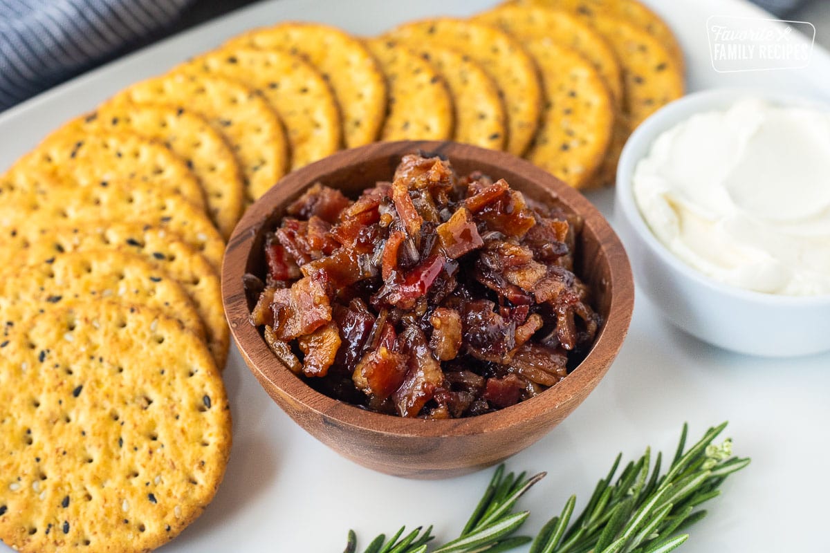 Bowl of bacon jam next to crackers and a bowl of cream cheese.