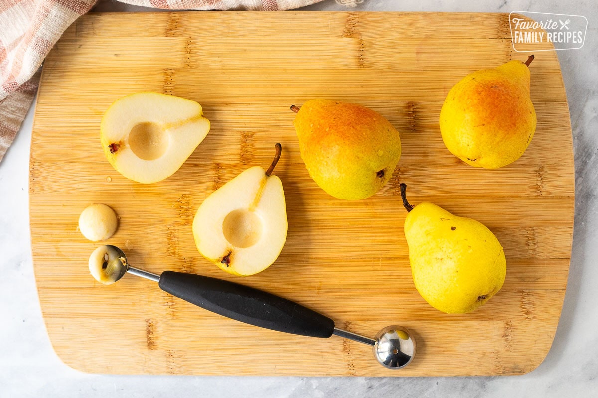 Sliced in half and cored pears on a cutting board.